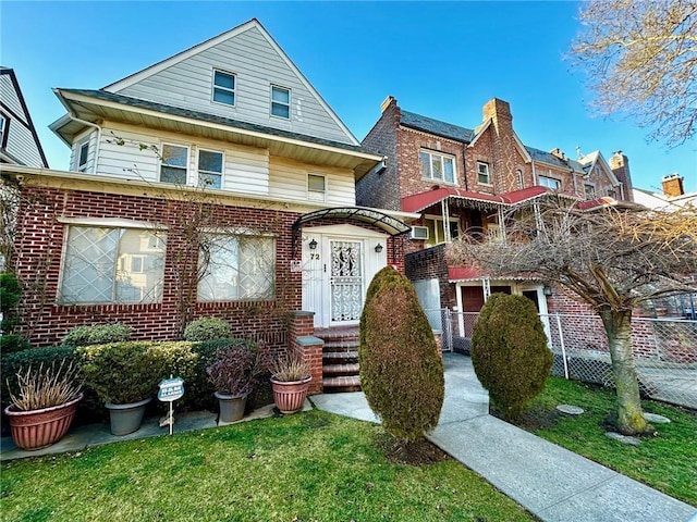 view of front of property featuring brick siding, a front lawn, and fence