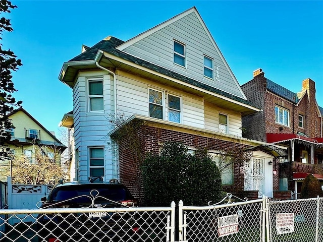 view of front facade with brick siding, a fenced front yard, and a gate