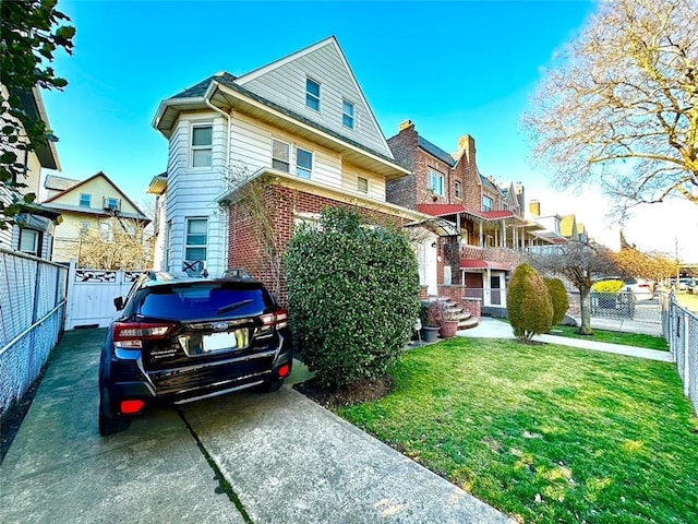 view of front facade featuring a front yard, brick siding, and fence