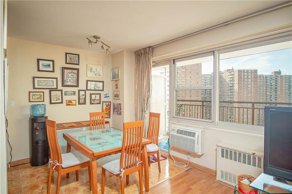 dining space featuring a wall mounted air conditioner, light wood-type flooring, and radiator