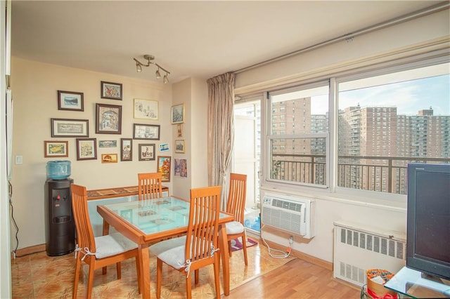 dining space featuring a wall mounted air conditioner, light wood-type flooring, and radiator