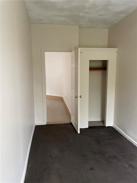 unfurnished bedroom featuring dark carpet and a closet