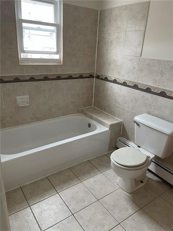 bathroom with tile patterned floors, bathtub / shower combination, tile walls, and toilet