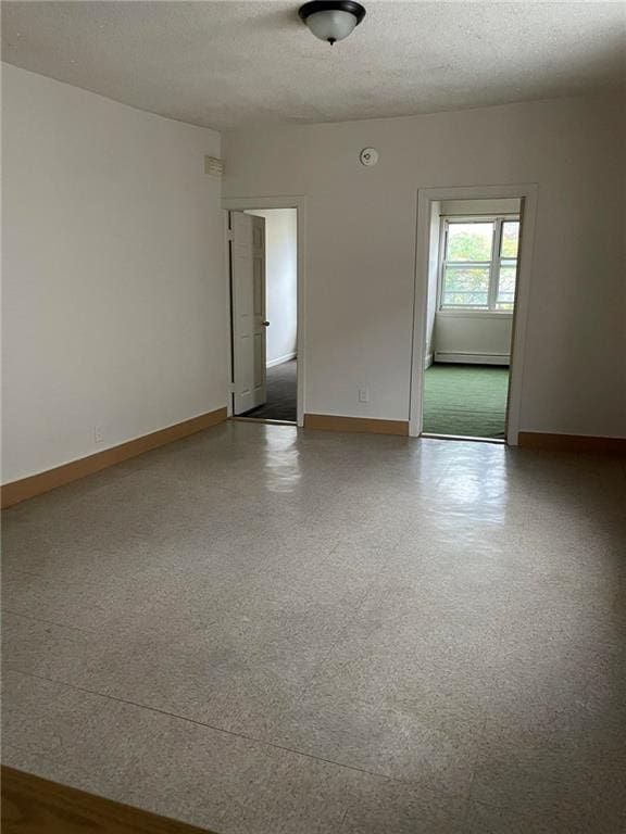 spare room with a textured ceiling and a baseboard heating unit