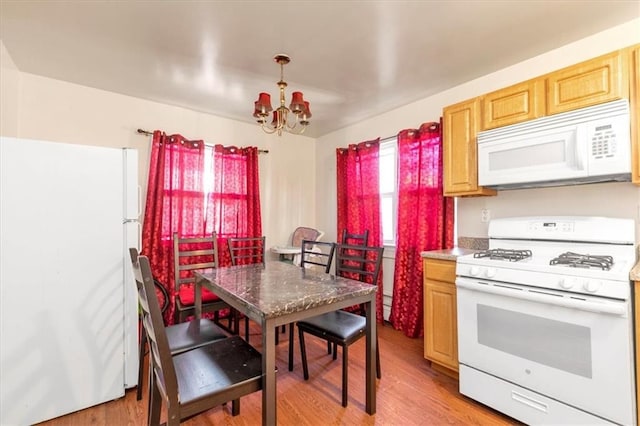 kitchen featuring light wood-type flooring, white appliances, light brown cabinets, a chandelier, and hanging light fixtures