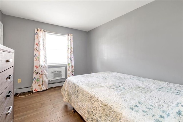 bedroom featuring hardwood / wood-style flooring, an AC wall unit, and a baseboard radiator