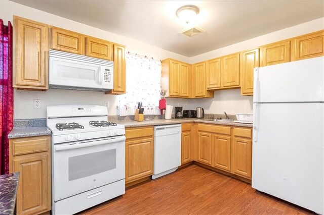 kitchen with hardwood / wood-style floors, white appliances, and sink