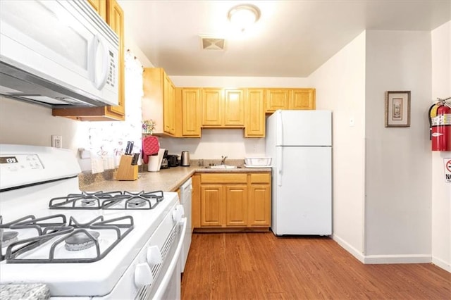 kitchen with light brown cabinets, white appliances, sink, and light hardwood / wood-style flooring