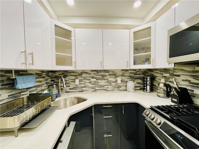 kitchen with stainless steel appliances, white cabinetry, sink, and tasteful backsplash