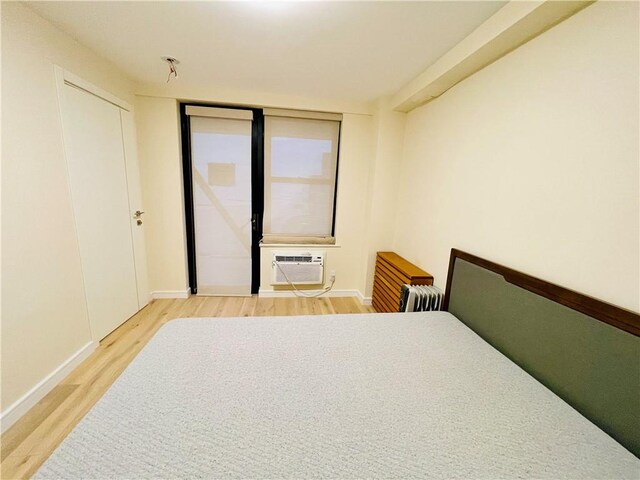 bedroom featuring a wall mounted air conditioner and wood-type flooring