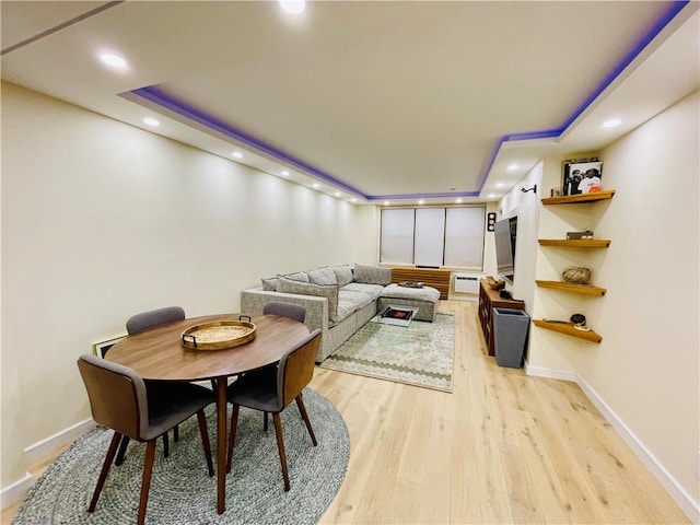 living area with light wood-style flooring, a tray ceiling, baseboards, and recessed lighting