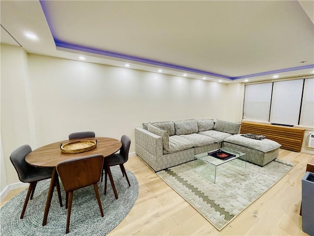 living room with recessed lighting, a raised ceiling, light wood-style flooring, and baseboards