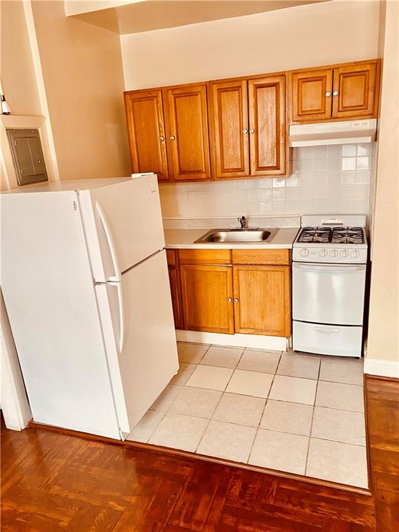 kitchen featuring tasteful backsplash, sink, light tile patterned floors, and white appliances