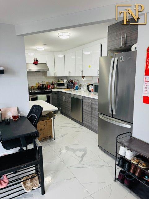 kitchen with appliances with stainless steel finishes, white cabinetry, sink, decorative backsplash, and dark brown cabinets