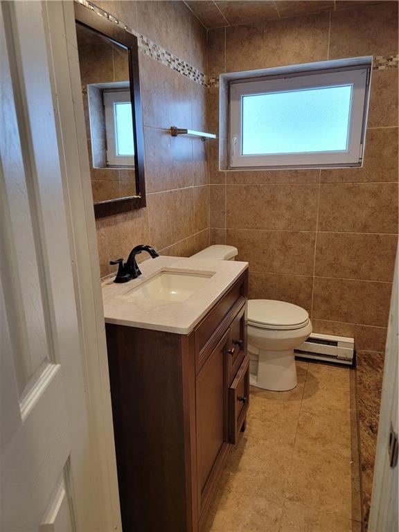 bathroom with vanity, toilet, tile walls, and baseboard heating