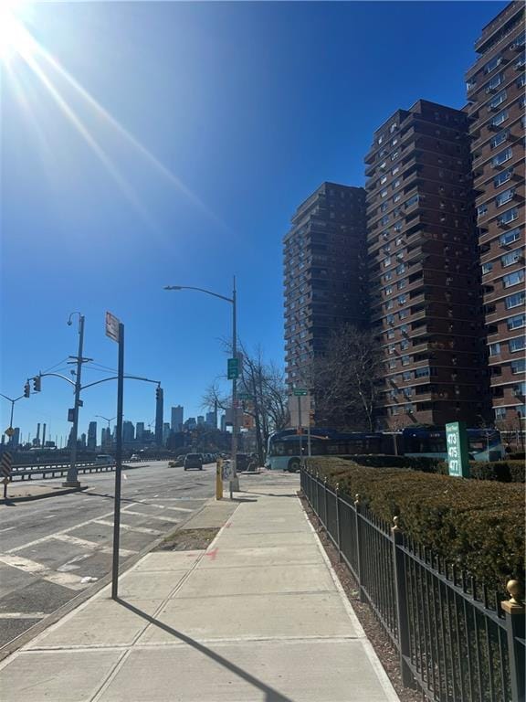 view of road featuring traffic lights, street lighting, a city view, curbs, and sidewalks