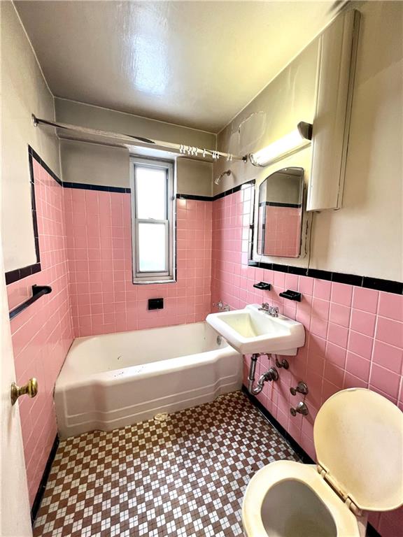 full bath featuring shower / bathing tub combination, a sink, tile walls, toilet, and tile patterned floors