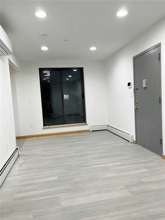 229 55th St Unit 5, Brooklyn, NY 11220 - unfurnished room with baseboard heating, recessed lighting, light wood finished floors, and a wall mounted air conditioner