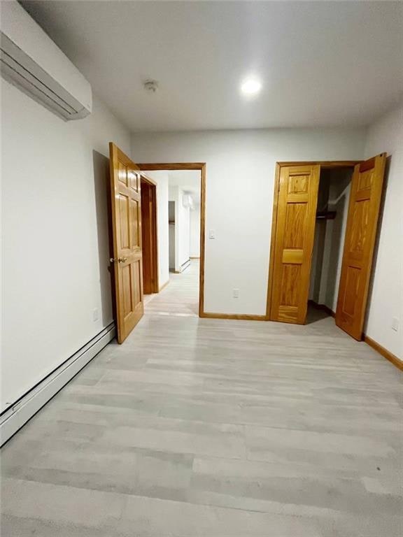 229 55th St Unit 5, Brooklyn, NY 11220 - unfurnished bedroom featuring a wall unit AC, light wood-style floors, baseboard heating, recessed lighting, and a closet