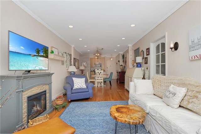 living room with ornamental molding, a stone fireplace, and wood-type flooring