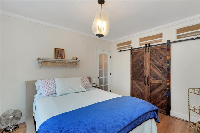 bedroom with hardwood / wood-style flooring, ornamental molding, and a barn door