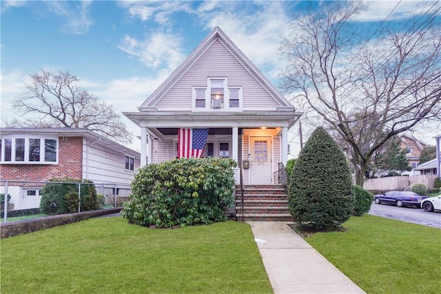 view of front of house with a porch, a front yard, and fence