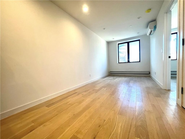 unfurnished room featuring a wall mounted AC, a baseboard heating unit, and light wood-type flooring