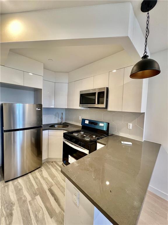 kitchen with white cabinets, sink, hanging light fixtures, and appliances with stainless steel finishes