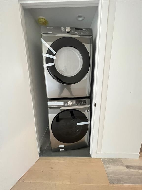 clothes washing area featuring stacked washer and clothes dryer and light wood-type flooring