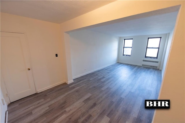 unfurnished room featuring radiator heating unit and dark hardwood / wood-style flooring