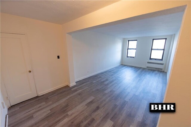 unfurnished room featuring dark wood-type flooring and radiator heating unit