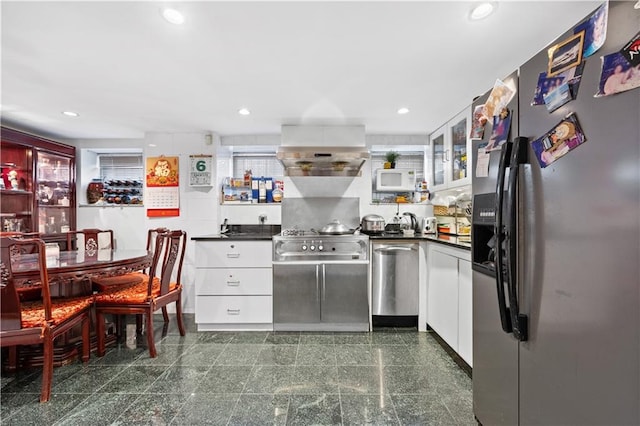 kitchen featuring ventilation hood, white cabinetry, and appliances with stainless steel finishes