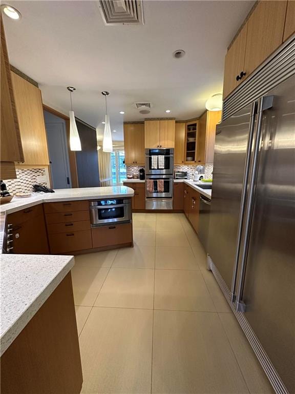 kitchen featuring backsplash, pendant lighting, light tile patterned floors, and stainless steel appliances