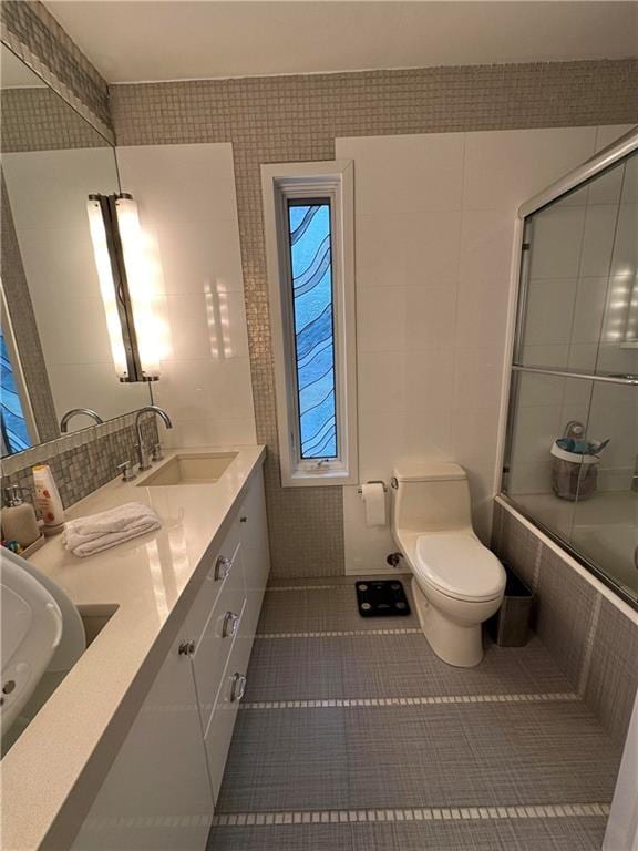 full bathroom with tile patterned flooring, vanity, toilet, and bath / shower combo with glass door