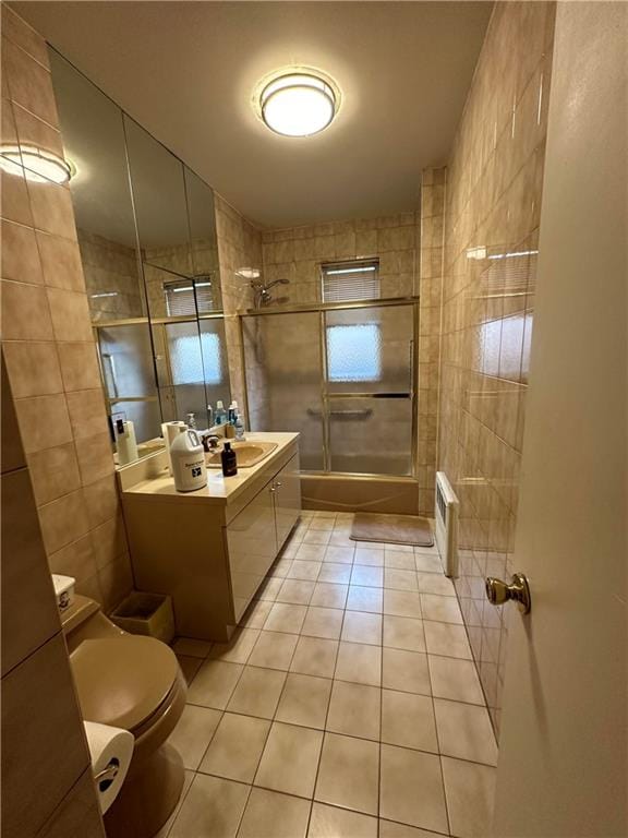 full bathroom with vanity, tile patterned floors, tiled shower / bath, toilet, and tile walls