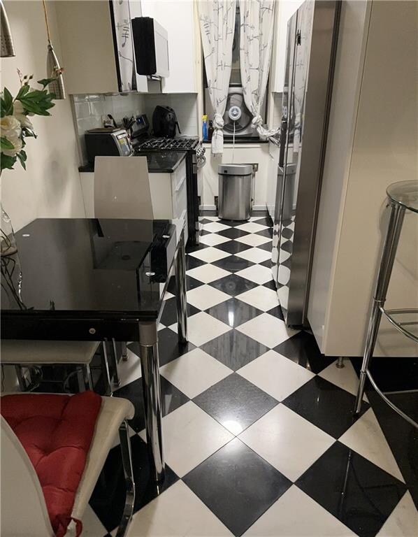 interior space with white cabinets, black range with gas cooktop, and decorative backsplash