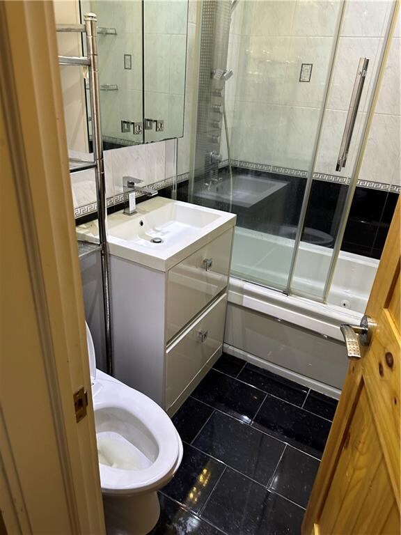 bathroom featuring tile patterned flooring, vanity, and combined bath / shower with glass door