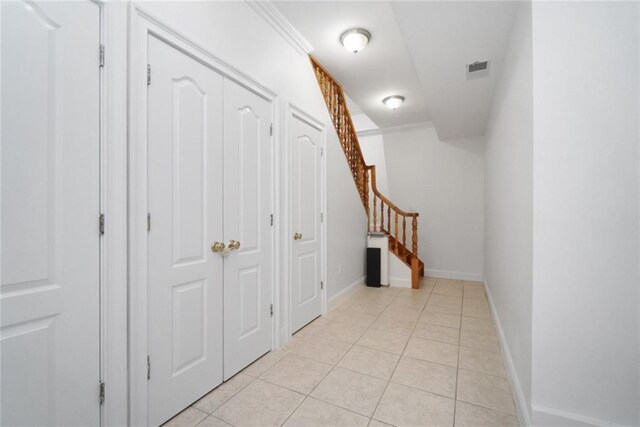 corridor featuring crown molding and light tile patterned flooring