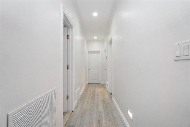 hallway with light wood-type flooring and ornamental molding