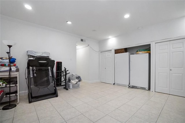 basement with white refrigerator, ornamental molding, and light tile patterned flooring