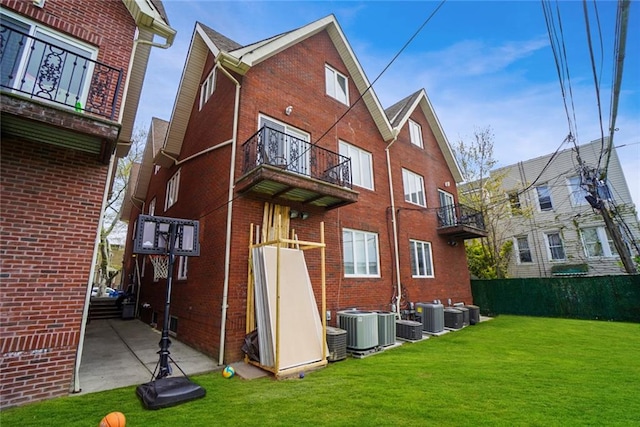 rear view of property featuring central AC unit, a lawn, and a balcony