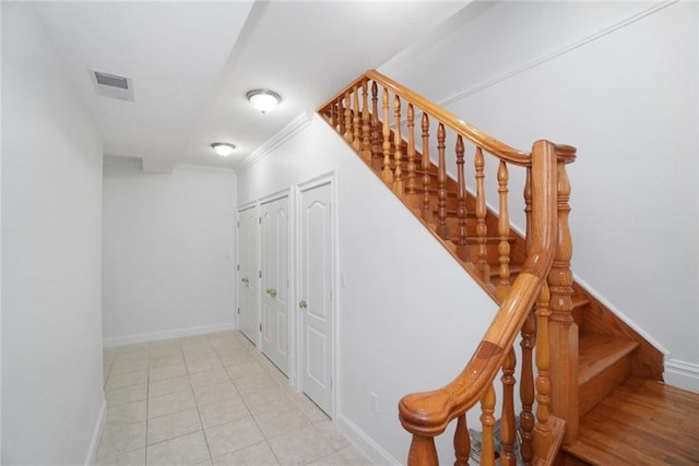 staircase featuring tile patterned flooring and crown molding