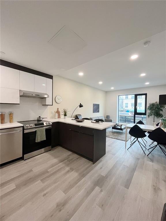 kitchen featuring white cabinets, appliances with stainless steel finishes, light wood-type flooring, and kitchen peninsula