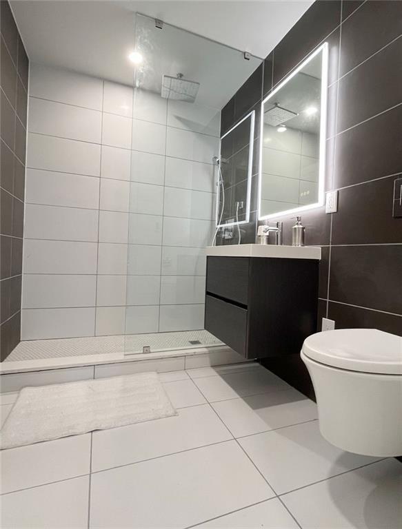 bathroom with vanity, tile patterned flooring, toilet, tile walls, and walk in shower