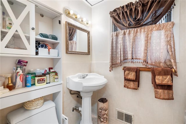 bathroom with toilet and tile walls