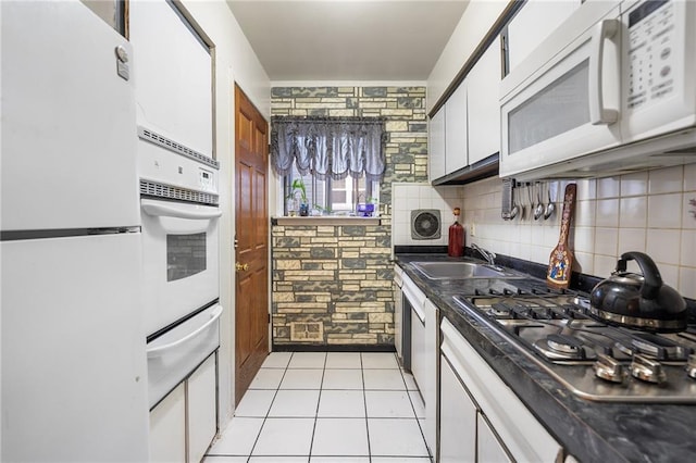 kitchen featuring white appliances, white cabinetry, light tile patterned flooring, and sink