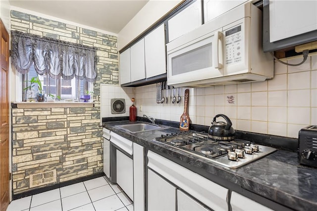 kitchen with sink, white cabinets, stainless steel gas cooktop, light tile patterned floors, and decorative backsplash