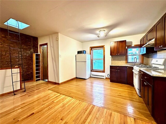 kitchen featuring white appliances, a skylight, light wood-type flooring, baseboard heating, and brick wall