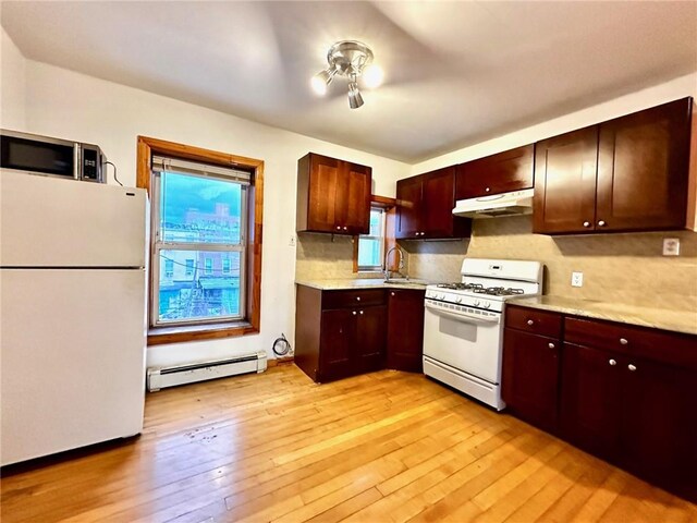 kitchen with sink, baseboard heating, tasteful backsplash, light hardwood / wood-style flooring, and white appliances