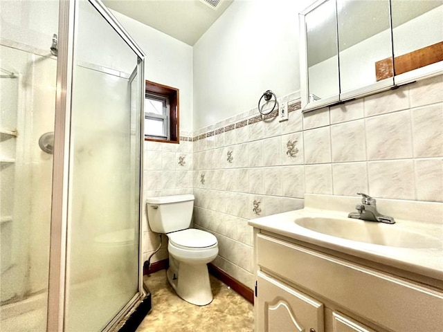 bathroom with vanity, toilet, a shower with door, and tile walls